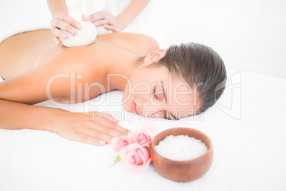 Beautiful brunette enjoying a herbal compress massage