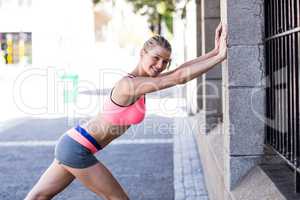 A beautiful woman stretching her body against a fence
