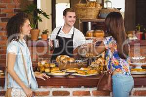 Smiling barista offering coffee to pretty customer