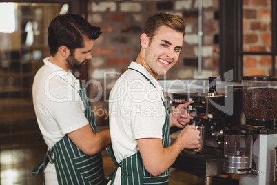 Two smiling baristas preparing coffee