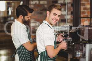 Two smiling baristas preparing coffee