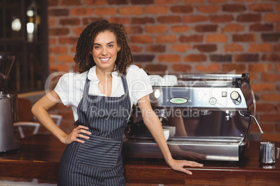 Pretty barista smiling in front of coffee machine