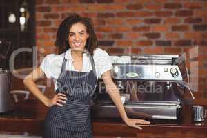 Pretty barista smiling in front of coffee machine