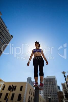 Athletic woman balancing on bollard