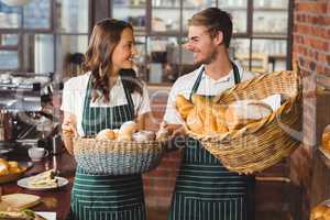 Smiling co-workers holding breads basket