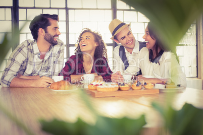 Laughing friends enjoying coffee and treats