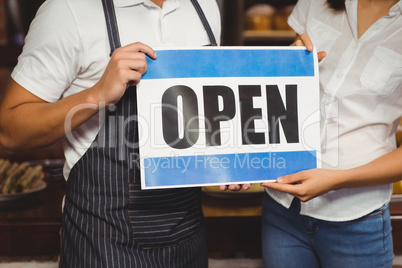 Waiter and waitress posing with open sign