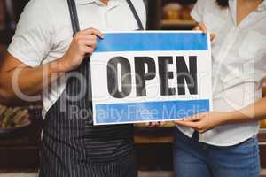 Waiter and waitress posing with open sign