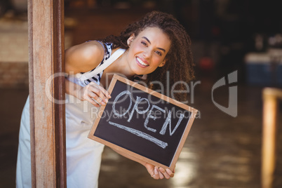 Hiding waitress showing chalkboard with open sign