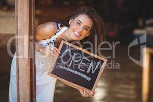 Hiding waitress showing chalkboard with open sign