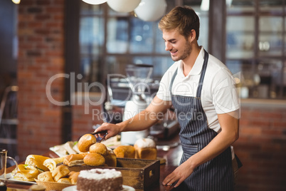 Handsome waiter picking up a roll