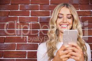 Beautiful blonde woman smiling and using smartphone