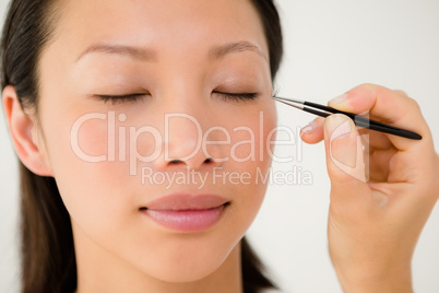 Woman placing fake eyelash on a patient