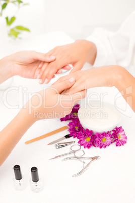 Beautician filing female clients nails at spa beauty salon