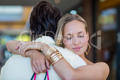 Smiling woman hugging her boyfriend with eyes closed