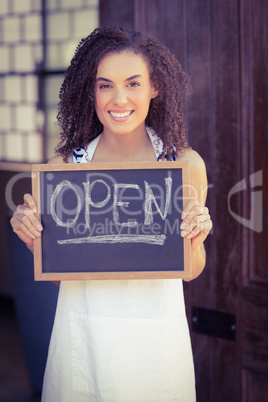 Smiling waitress showing chalkboard with open sign