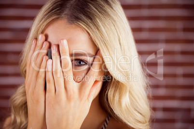 Beautiful blonde woman hiding behind hands