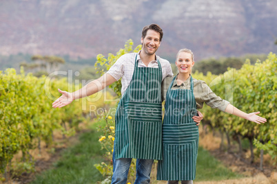 Two young happy vintners showing their fields