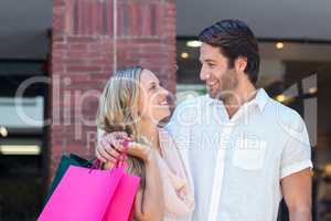 Smiling couple with shopping bags embracing