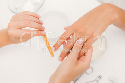 Beautician filing female clients nails at spa beauty salon