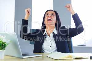 Businesswoman cheering at her desk