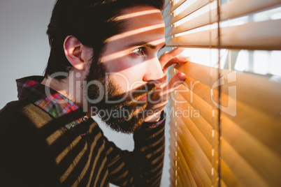 Hipster businessman peeking through blinds