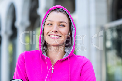 Portrait of a woman wearing a pink jacket putting her headphones