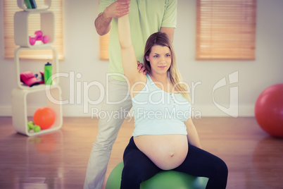 Pregnant woman having relaxing massage while sitting on exercise