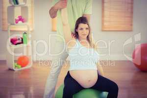 Pregnant woman having relaxing massage while sitting on exercise