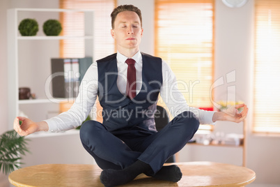 Calm businessman meditating in lotus pose