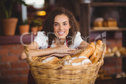 Smiling waitress bended over a basket of bread