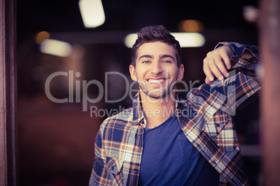 Smiling casual waiter leaning against door