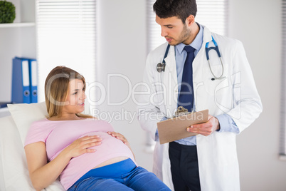 Doctor giving advice to lying pregnant patient