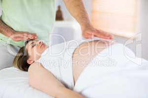 Relaxed pregnant woman getting reiki treatment