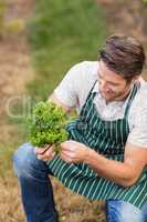 Young happy farmer looking at vegetable