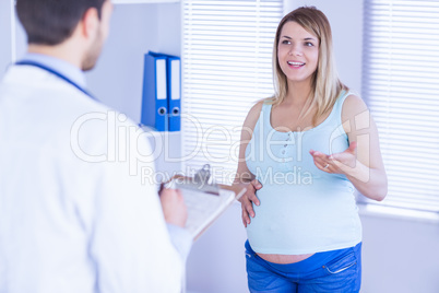Smiling pregnant patient talking to doctor which is taking notes