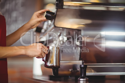 Barista steaming milk at the coffee machine