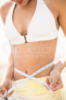 Pretty woman in bikini measuring her waist