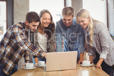 Smiling friends standing and pointing on laptop screen