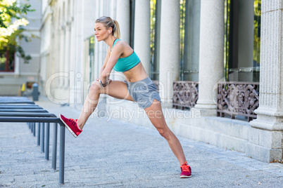 A beautiful woman stretching her leg against pipes