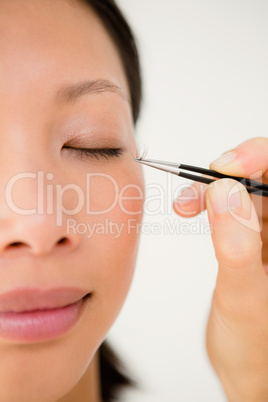 Woman placing fake eyelash on a patient