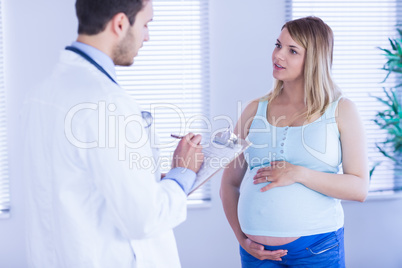 Pregnant patient talking to doctor which is taking notes
