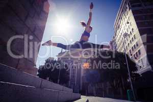 Athletic woman jumping off the stairs and doing split in the air