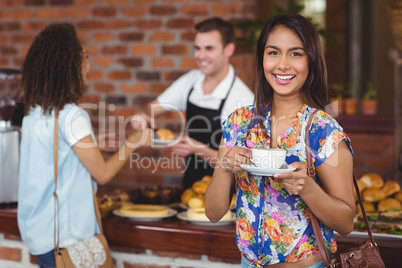 Smiling pretty customer holding cup of coffee