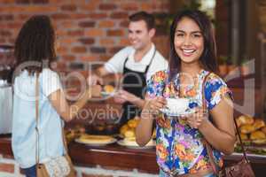 Smiling pretty customer holding cup of coffee