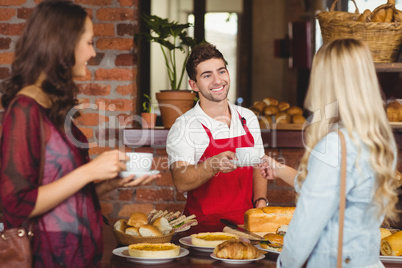 Smiling waiter serving a coffee to a customer