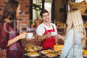 Smiling waiter serving a coffee to a customer