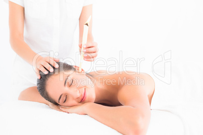 Beautiful woman receiving ear candle treatment at spa center