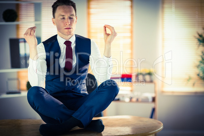 Calm businessman meditating in lotus pose