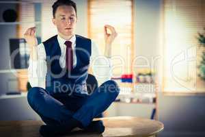 Calm businessman meditating in lotus pose